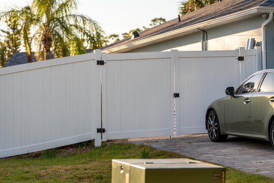 White vinyl privacy fence enclosing suburban backyard in Florida. Modern residential landscaping, durable PVC construction and clean neighborhood design.
