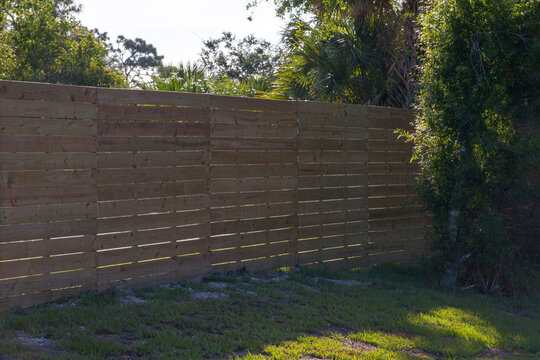 Wooden picket fence on green lawn surrounding property grounds for backyard protection and privacy.