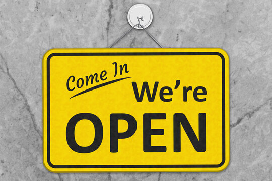 Come in, We are Open yellow and black sign on grey stone
