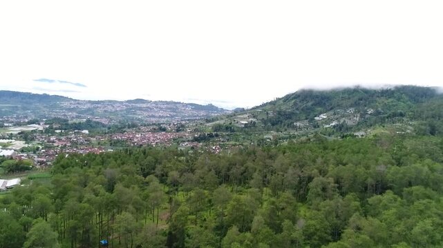 Aerial video of pine forest and misty highlands with city view near Tangkuban Parahu, Lembang, Bandung, West Java, Indonesia