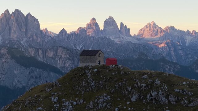 Aerial 3x telephoto view of Rifugio Tiziano and Bivacco Toso at sunset in the Marmarole Dolomites, with Tre Cime di Lavaredo in the background.