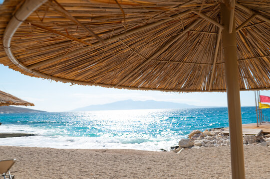 Thatched beach umbrella provides shade beside the sea at a coastal beach during daytime