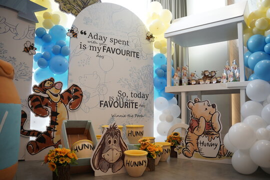 Winnie the Pooh themed children&rsquo;s birthday party decoration featuring character cutouts, honey pots, balloons and a colorful dessert display.