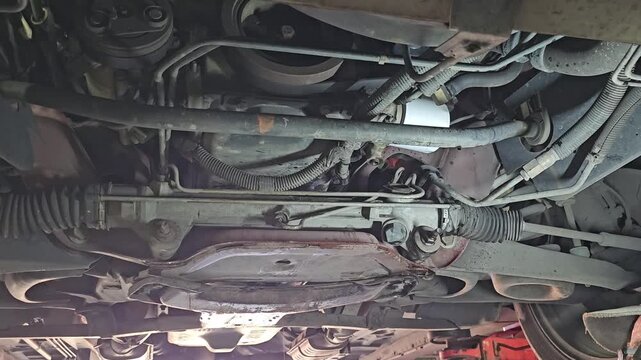 Mechanic inspects the underside of a car on a vehicle lift in a repair shop