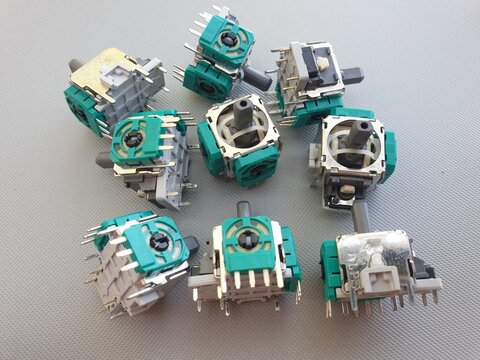 Replacement Analog Joystick Components Scattered on a Grey Surface