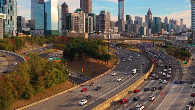 Atlanta, Georgia skyline with skyscraper buildings and expressway stretching across the city. Dense highway traffic and modern transportation infrastructure.