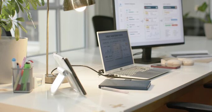 Camera is racking focus after lens shift to silver laptop and monitor near window, revealing data
