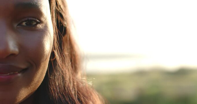 Mid-adult woman smiling laughing as sunlight backlit hair showing hoop earring at coast, copy space