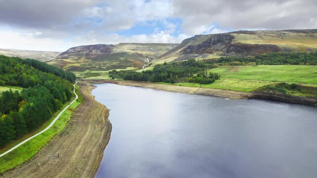Rolling hills stretch under a cloudy, blue sky cutting through open moorland