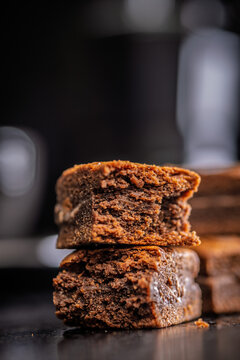 Close-Up Stack Of Chewy Chocolate Brownies With Crumbly Texture On Dark Surface
