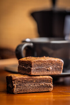 Stacked Chocolate Brownies With Coffee Mug In Cozy Cafe Setting, Close-Up Dessert Photo
