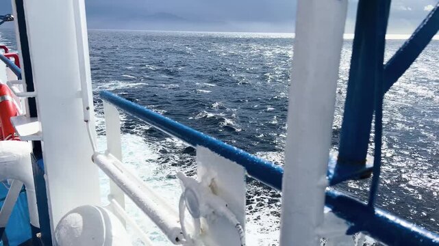 View from a boat deck showing railing and ocean wake