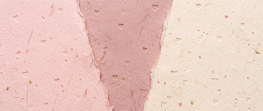 Handmade textured paper background with torn edges in shades of soft pink and beige featuring tiny embossed heart symbols and gold specks for elegant wedding stationery card layout