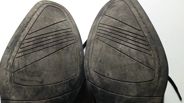 Close up top view of worn shoe soles from black leather mens dress shoes on white background