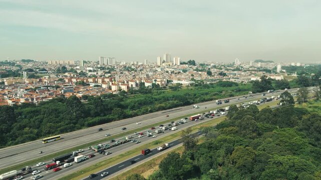 Aerial view of highway traffic beside green forest in Sao Paulo