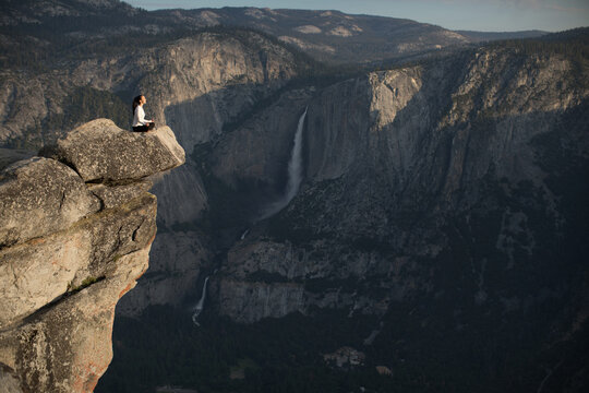 Peaceful woman on cliff edge overlooking waterfall Yosemite national park during the morning light of summer