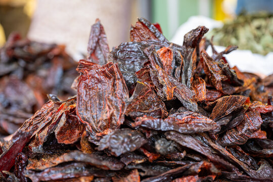 Dried chili pepper pieces displayed in bulk at a market in Huancayo, Peru. Close-up of dark red dehydrated peppers cut into irregular pieces, highlighting their leathery texture.