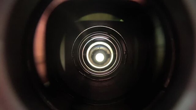 Extreme macro perspective looking through camera lens elements showing crosshair reticle and concentric reflections