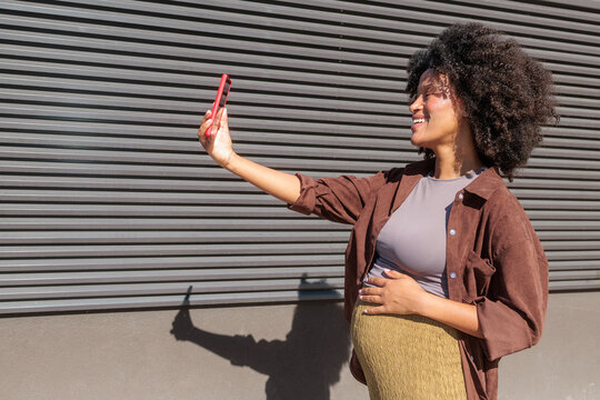 Pregnancy and digital connection, pregnant woman taking a selfie