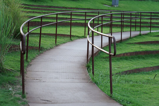 The small path with wrought iron railings among the grass in the park