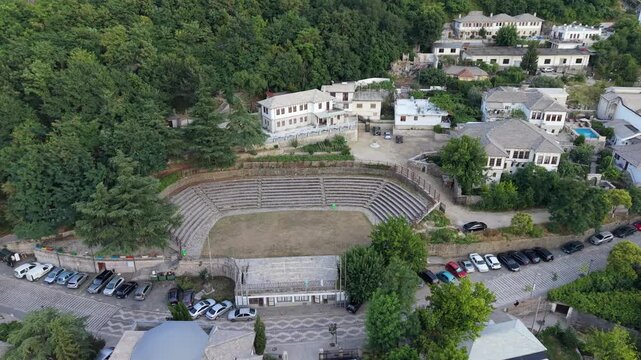 Aerial view of an open-air amphitheater surrounded by trees and buildings in Gjirokastra, Albania.