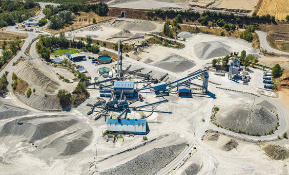 Aerial view of a sand and gravel processing complex with conveyor belt networks, concrete silos, aggregate stockpiles and water treatment tanks in Valence, Auvergne-Rhone-Alpes, France.