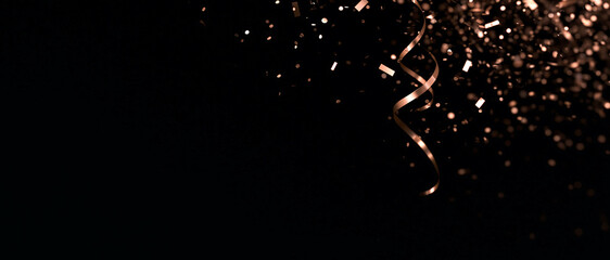 Obraz na płótnie Canvas Rose gold confetti and spiral ribbon falling on black background. Panoramic celebration banner with copy space for holiday, party, and luxury event