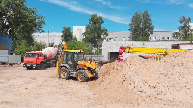Backhoe loader moving sand at a construction site