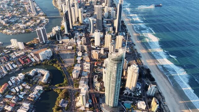 High-altitude aerial drone view of the row of high-rise buildings between the beach and canals with a ship at sea, Surfers Paradise, Australia.