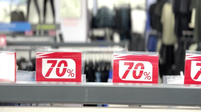 70% off retail sale &mdash; three red signs on shelf, blurred store background, close‑up