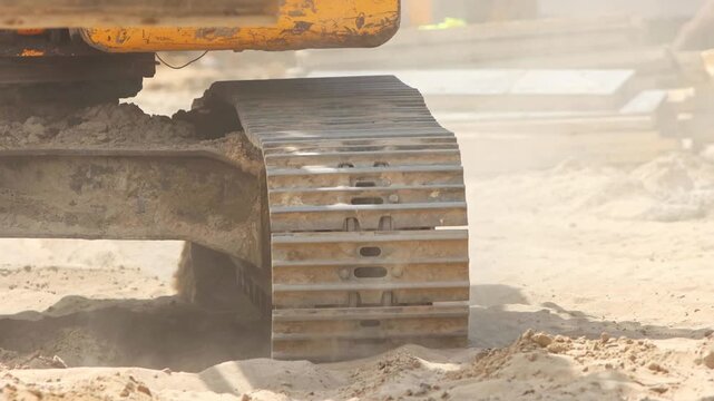 Excavator continuous tracks moving on sandy ground