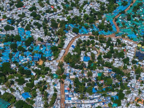 Ukhia, Bangladesh - 14 October 2026: Aerial view of Rohingya Camp E-Block featuring dense clusters of makeshift shelters with blue tarps, narrow dirt paths, and scattered trees.