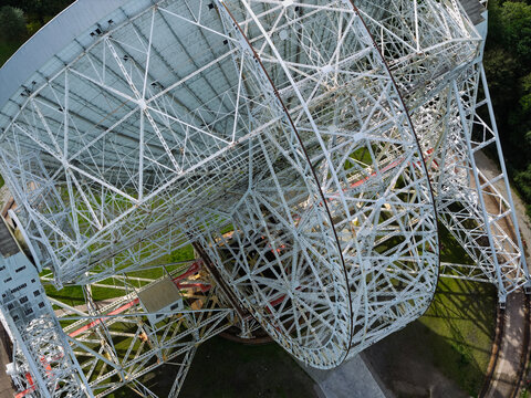 Aerial view of the Lovell Telescope at Jodrell Bank Observatory, featuring its massive white steel lattice structure and parabolic dish set against green grounds in the United Kingdom.
