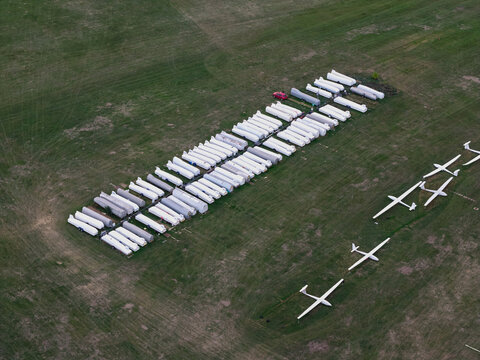 Aerial view of numerous gliders and sailplanes parked in organized rows on a grassy airfield in the United Kingdom.