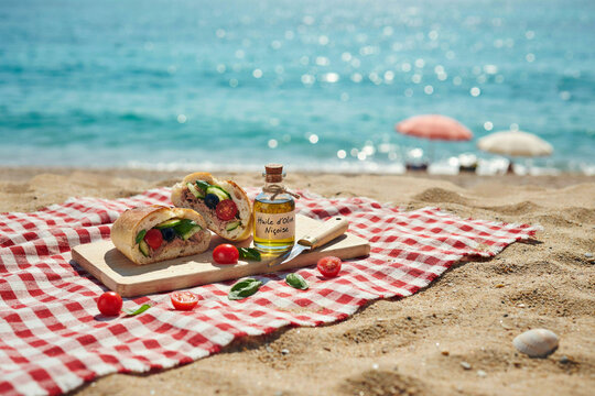 Pique-nique sur la plage avec sandwich pan bagnat au thon, huile d'olive et tomates cerises face &agrave; la mer en &eacute;t&eacute;