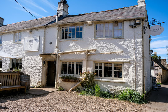 Langford, UK - April 6, 2026. Traditional Historic Country Pub The Bell Inn in Langford Village Cotswolds. A high-detail horizontal photograph capturing the exterior facade of The Bell Inn, a classic 