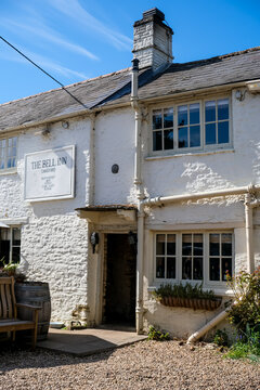 Langford, UK - April 6, 2026. Traditional Historic Country Pub The Bell Inn in Langford Village Cotswolds. A high-detail horizontal photograph capturing the exterior facade of The Bell Inn, a classic 