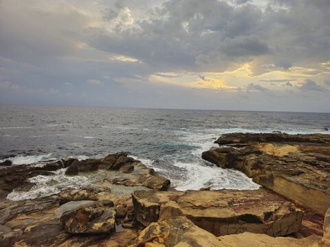 Waves surging into a rocky inlet between golden ledges, Marsaskala