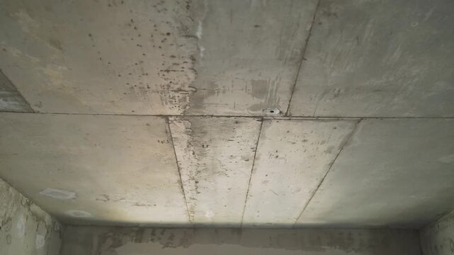 Camera slowly zooms in on a raw concrete ceiling in an unfinished building. Close up on the rough texture, panels, joints. Industrial, minimalist, grunge background for construction renovation