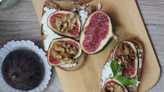 Toasted whole wheat bread with figs, ricotta (cream cheese),mint, honey served on white wooden cutting board. Healthy food concept.