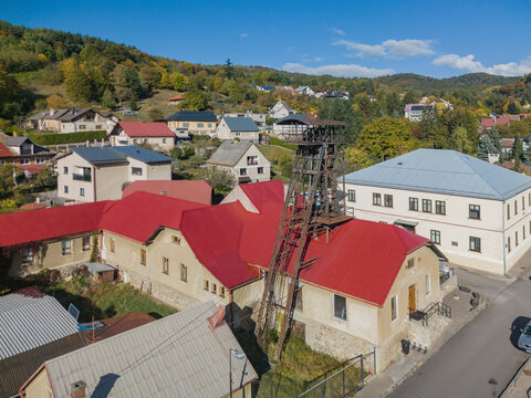 Aerial view of Jama Ferdinand headframe standing above historic mining buildings with red roofs in a rural town setting, Ziar nad Hronom, Banskobystricky kraj, Slovakia.
