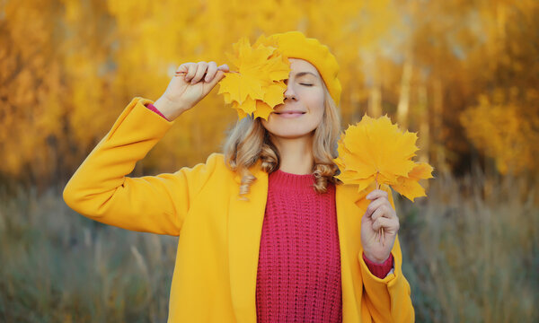 Happy woman with autumn yellow leaves, cheerful girl smiling outdoors