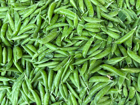 Pile of fresh snap peas at a market stand
