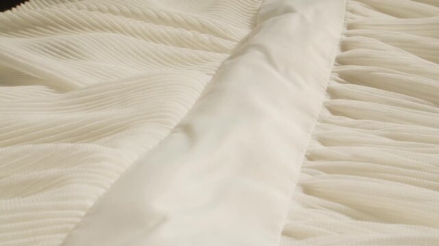 Ribbed fabric texture in cream color, close up of soft pleated knit textile with hand touching, beige knitted cloth background for fashion design and interior upholstery