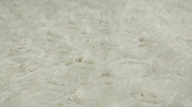 White fur texture with hand touching, close up of fluffy faux fur and natural sheepskin rug, soft long hair fur background in fur shop from Turkish fur factory production