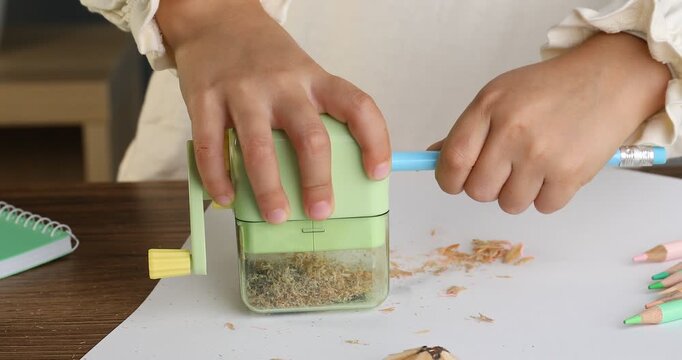 Child using hand-cranked sharpener at table, closeup