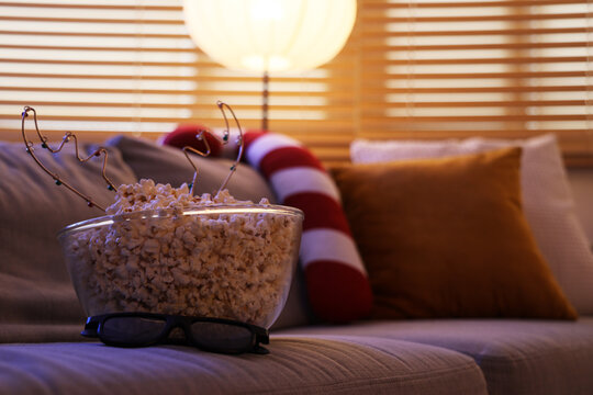 Christmas movie night, holiday entertainment and festive home cinema with popcorn bowl, 3d glasses and reindeer antlers on a cozy living room sofa