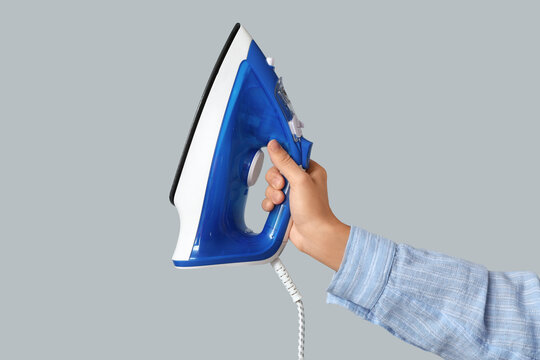 Household chores and laundry care, person holding a modern steam iron for garment maintenance and clothing maintenance on a neutral background