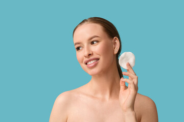 Skincare routine and facial cleansing, young woman using cotton pad for makeup removal on blue background © Pixel-Shot