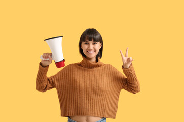 Announcement and social activism, young woman holding a megaphone and showing a peace sign for...
